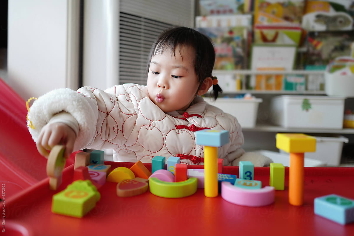 Asian baby builds blocks alone