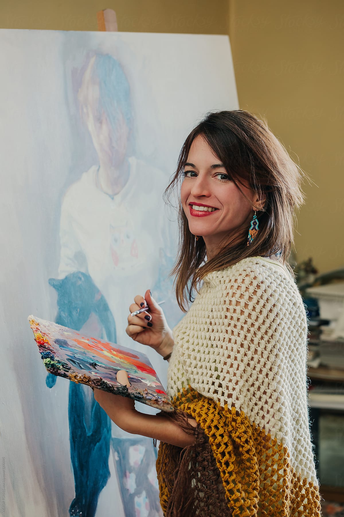 Portrait of a happy woman working on an oil painting in her stud