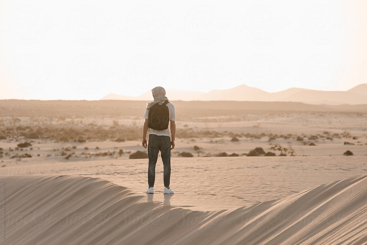 Man standing among many hot sand in desert.