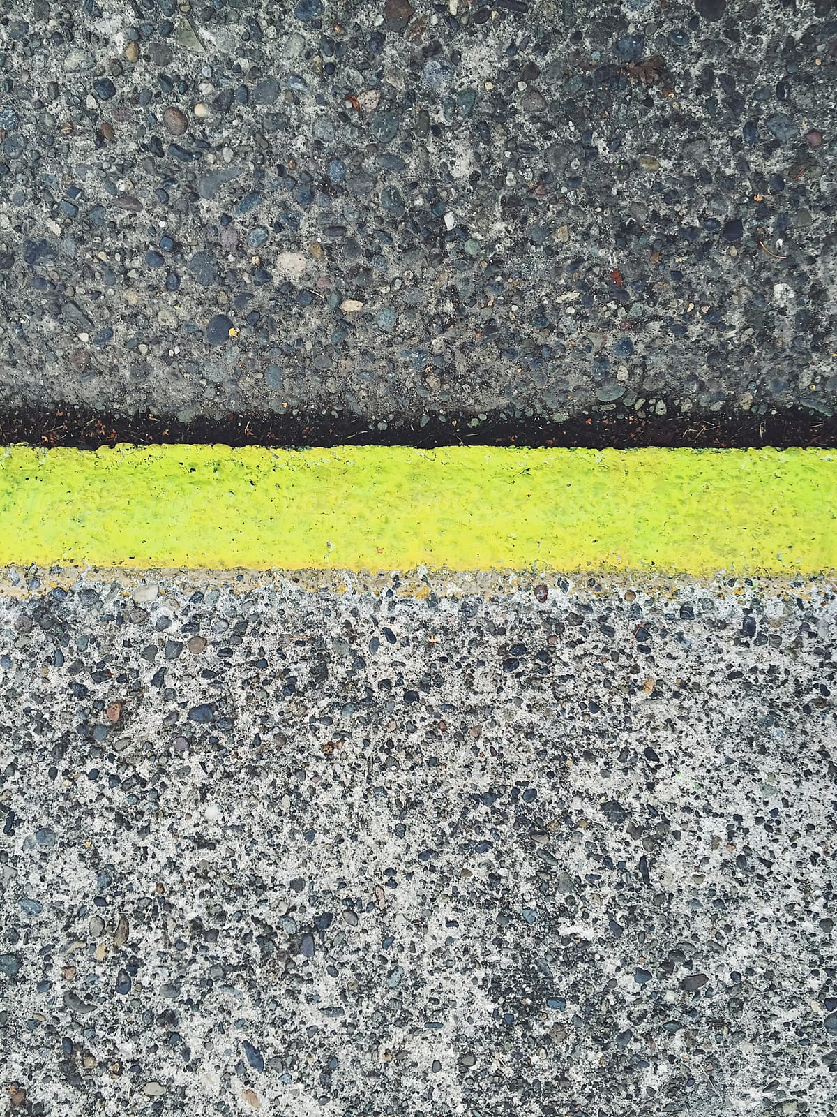 Painted yellow curb along sidewalk and street, close up