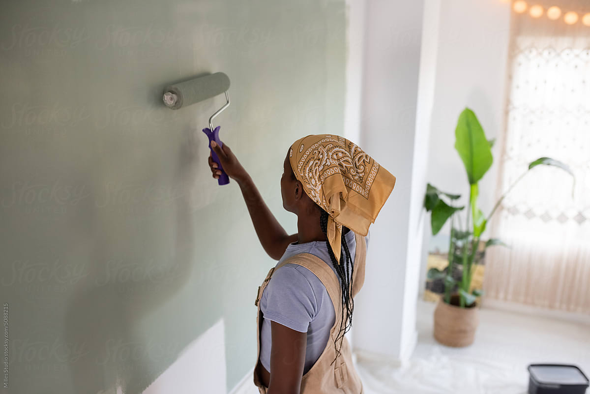 African American woman using roller to paint wall