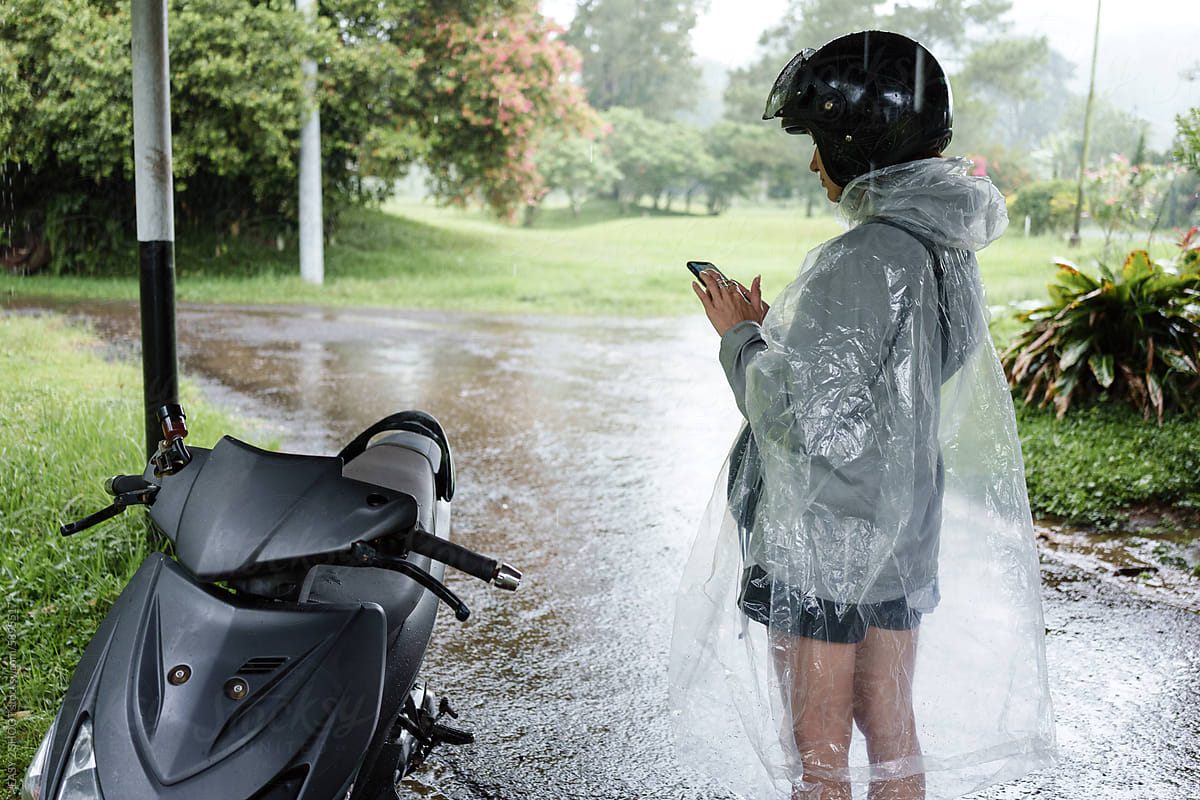 Person Wearing Rain Poncho Standing by Motorcycle
