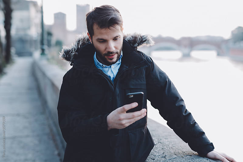 Man holding mobile phone during a cold evening