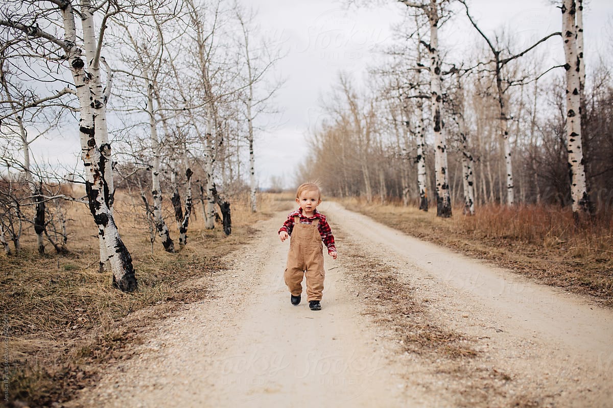 Toddler boy walking down road in bib overalls