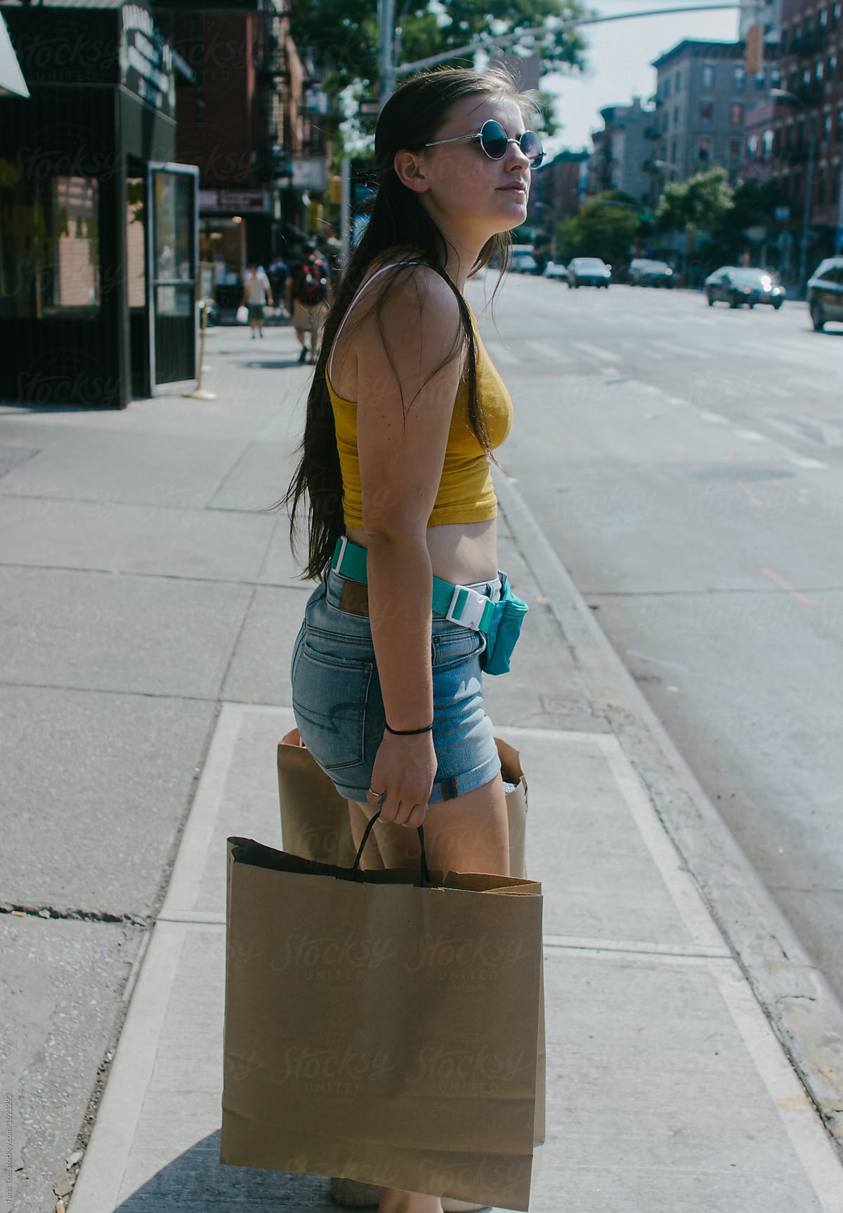 teenager holding shopping bags standing on city sidewalk