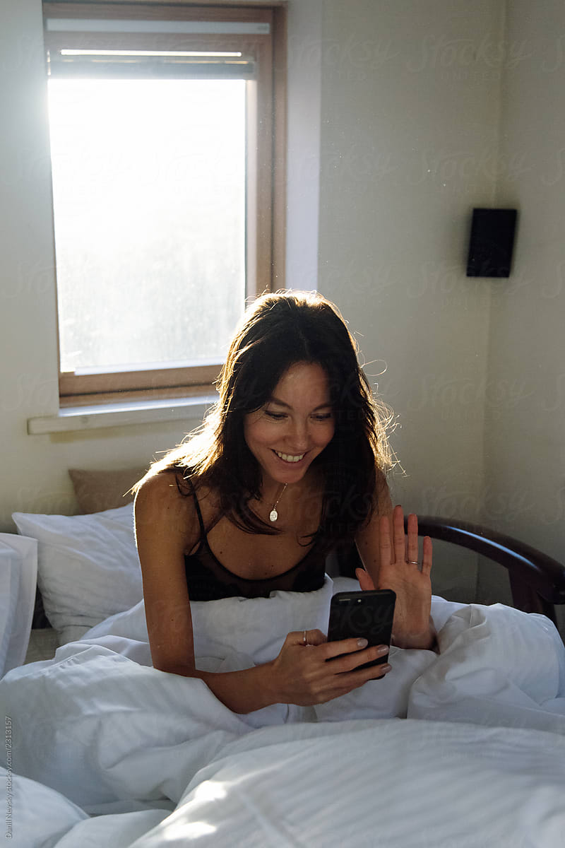 Cheerful Woman Making Video Call From Bed By Stocksy Contributor Danil Nevsky Stocksy 