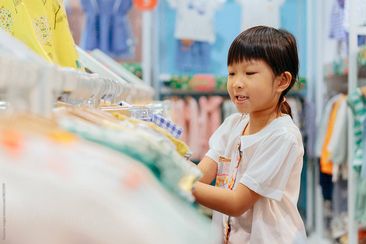 Asian little girl choosing clothes in clothing store