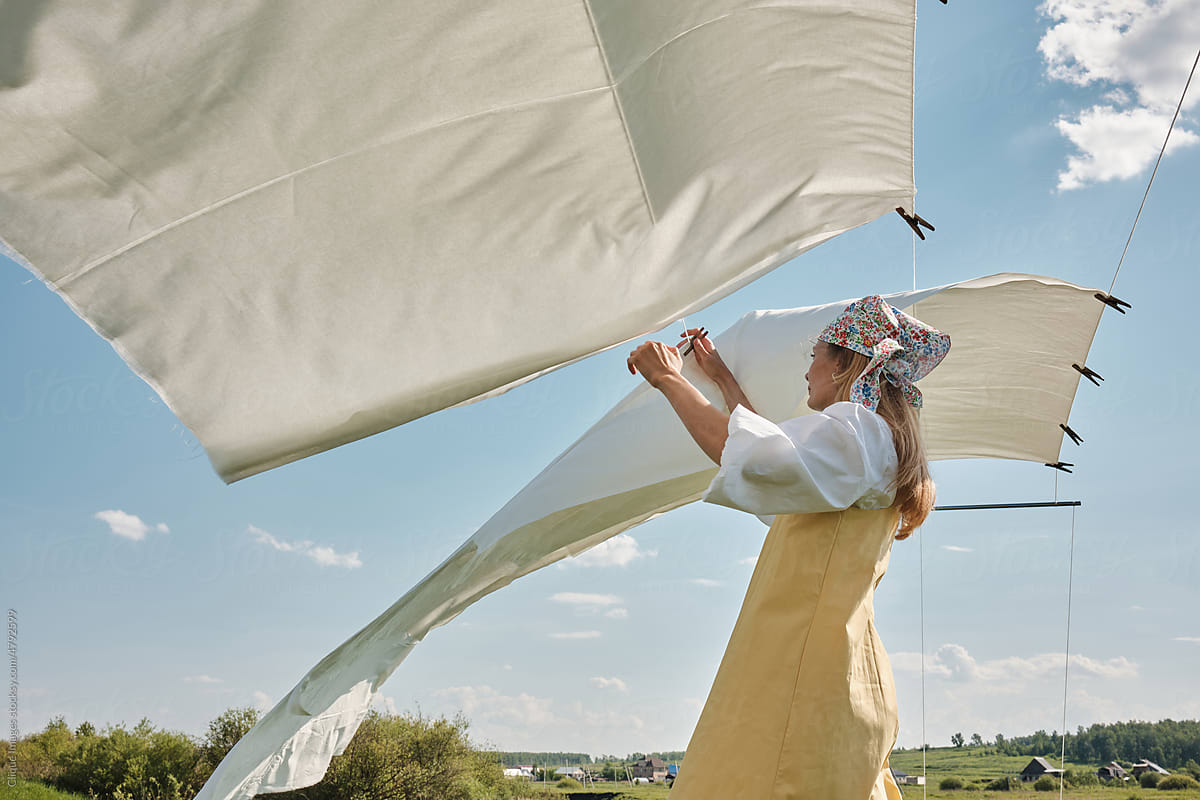 Woman Taking Off Dry Linen On Windy Day