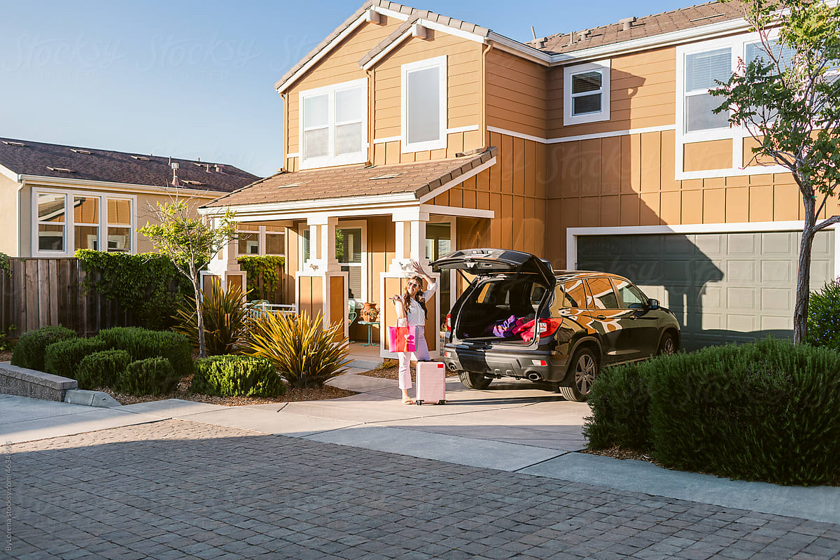 Woman with suitcases in front garage California houses