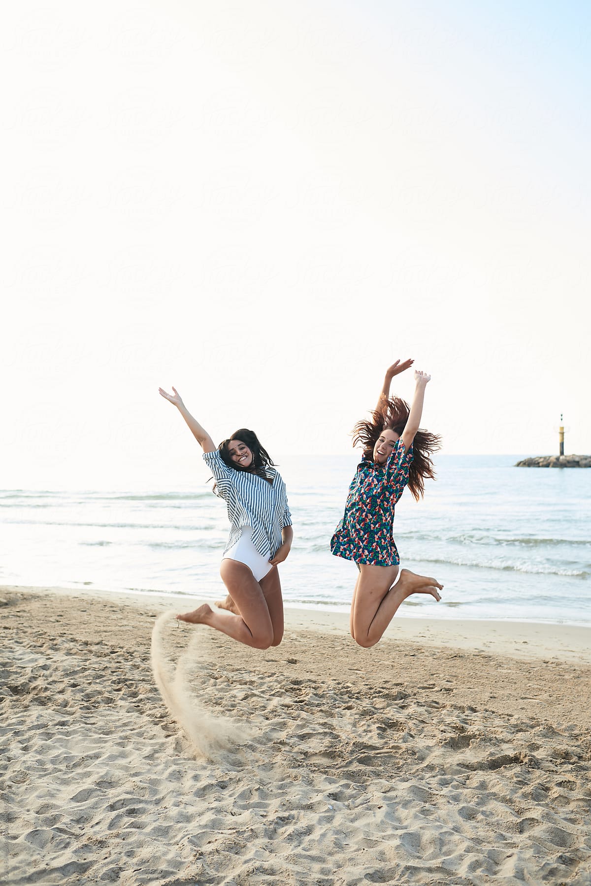 Happy women jumping together on beach