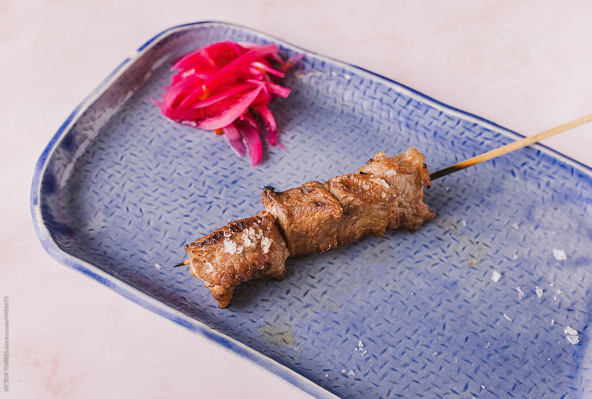 Delicious roasted meat skewer on blue plate