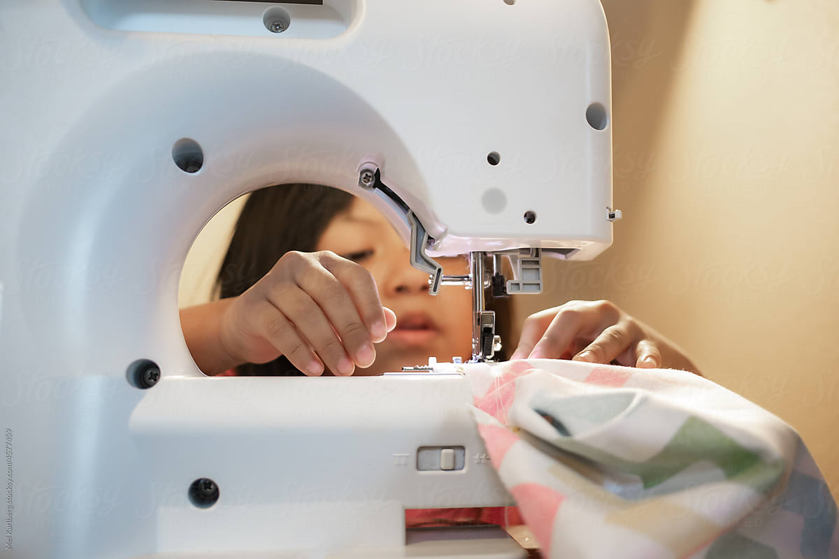 Young girl concentrating while learning to sew on sewing machine