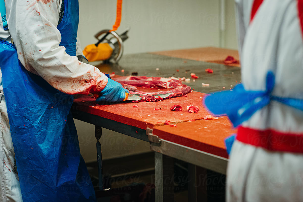 Butcher cutting meat in a factory