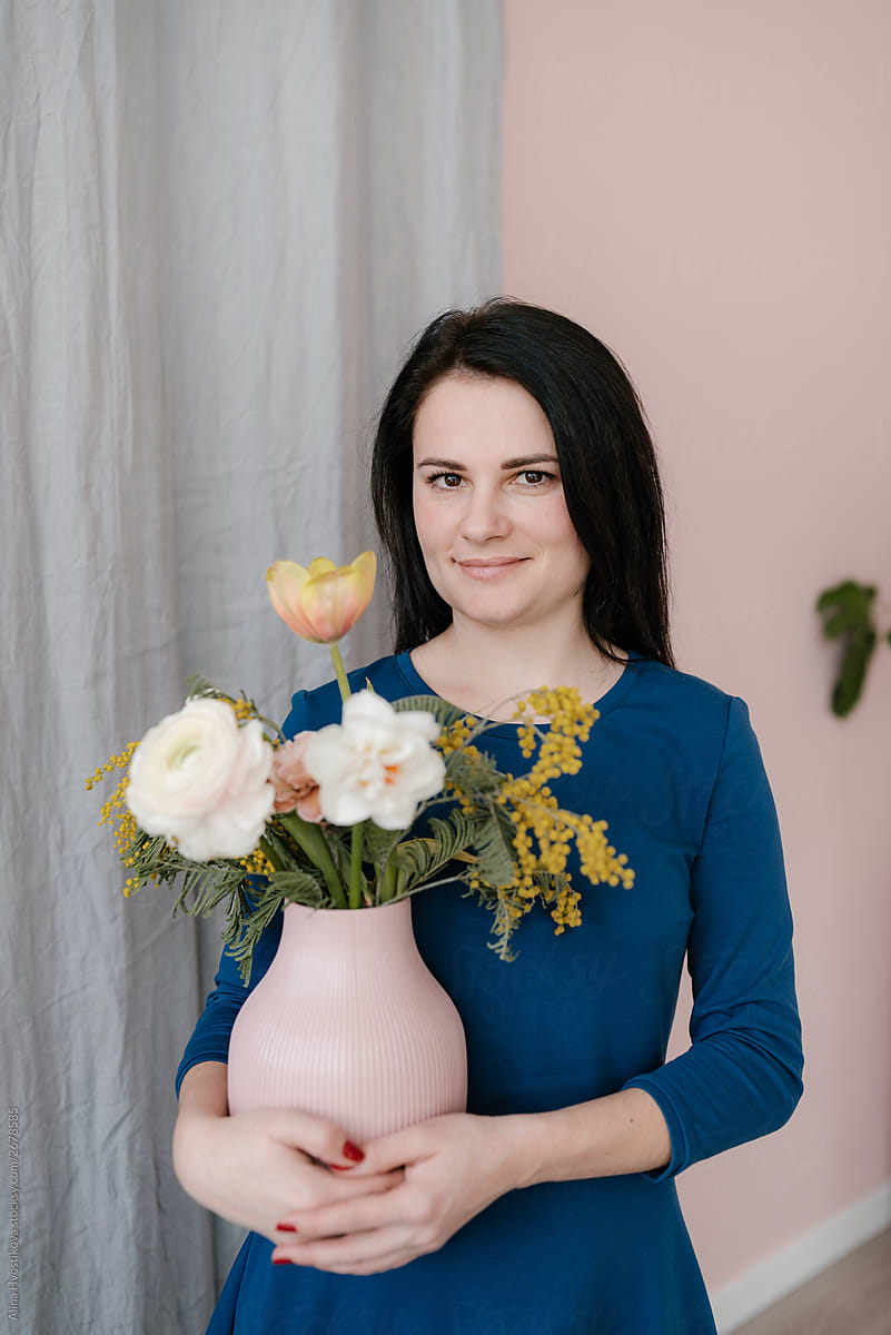 Beautiful brunette woman holding pink vase with bouquet.