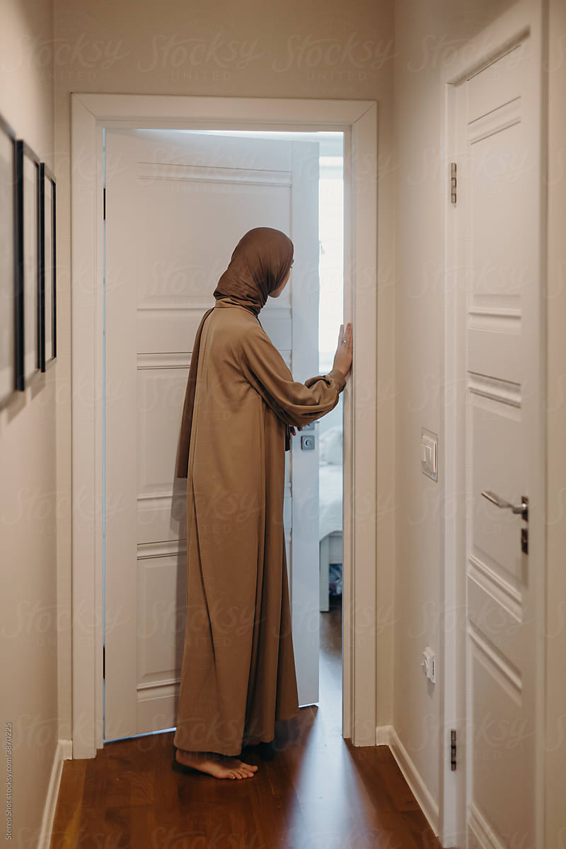 Muslim woman closing door of room at home