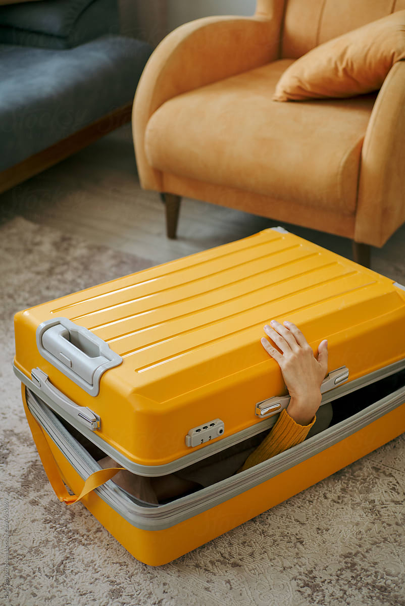 An unrecognizable person packed into a travel suitcase