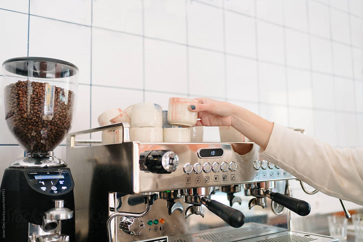 Barista arranging cups on coffee machine