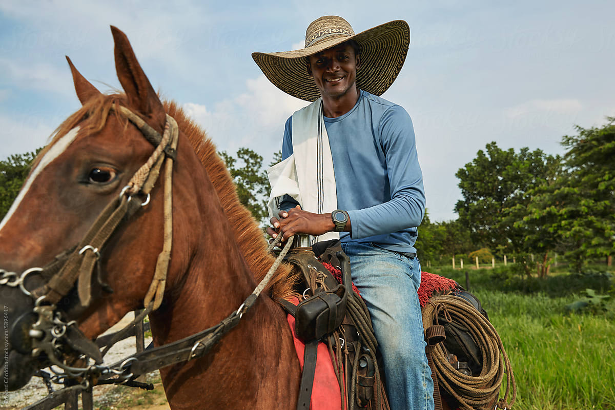 Smiling cowboy portrayed riding on his horse on a Colombian farm