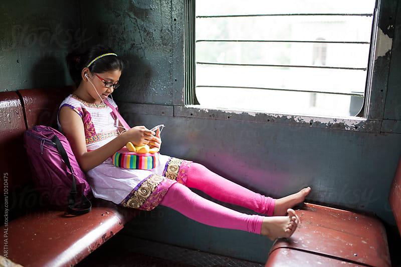 A teenage girl traveling in a local train and using smartphone