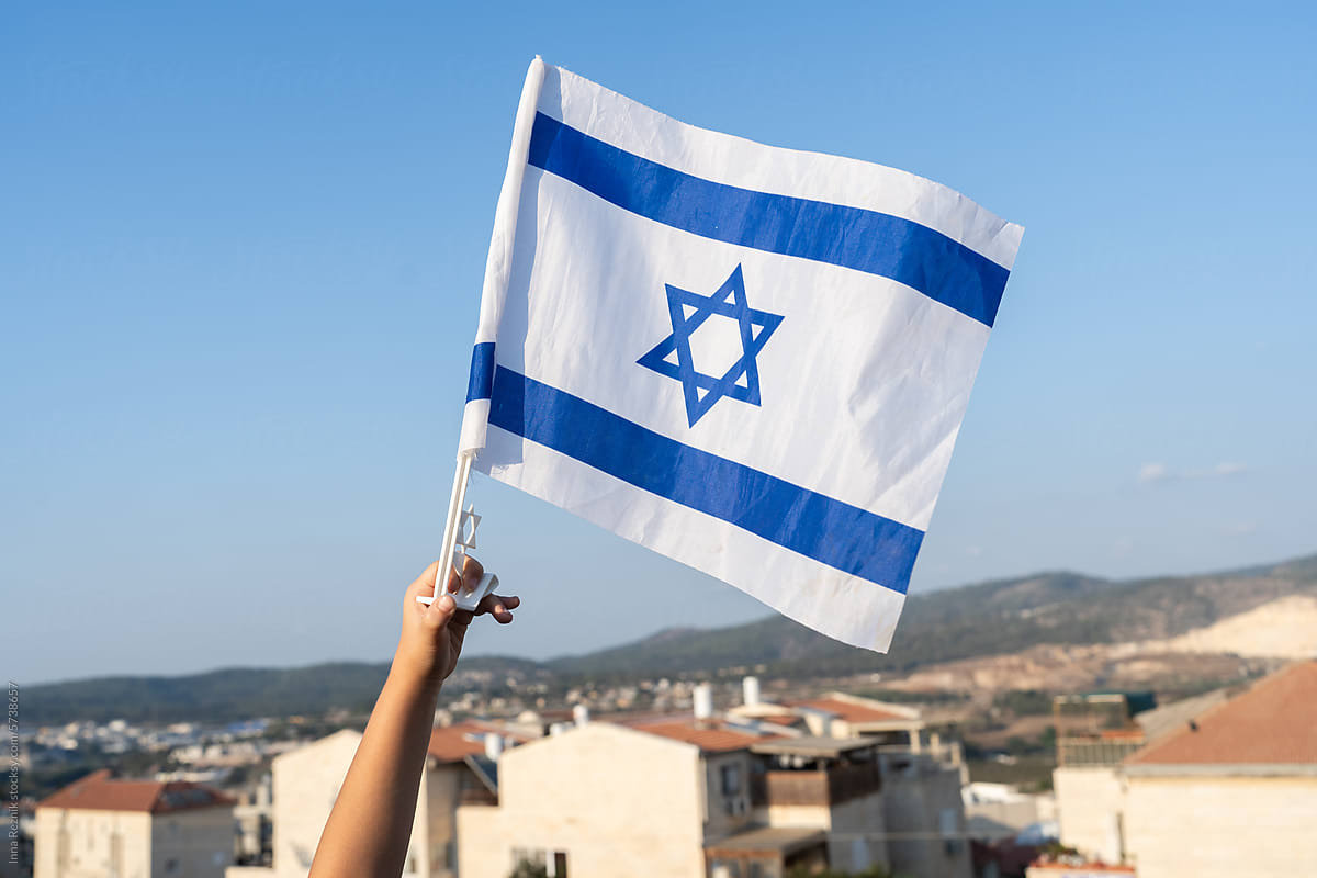 Child\'s Hand with Israeli Flag on Israel View Background.