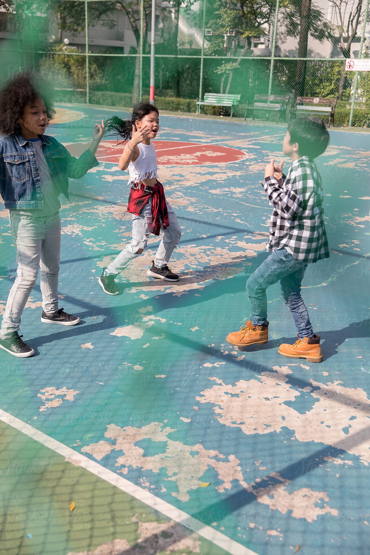 Group of three kids dancing together outside at the playground