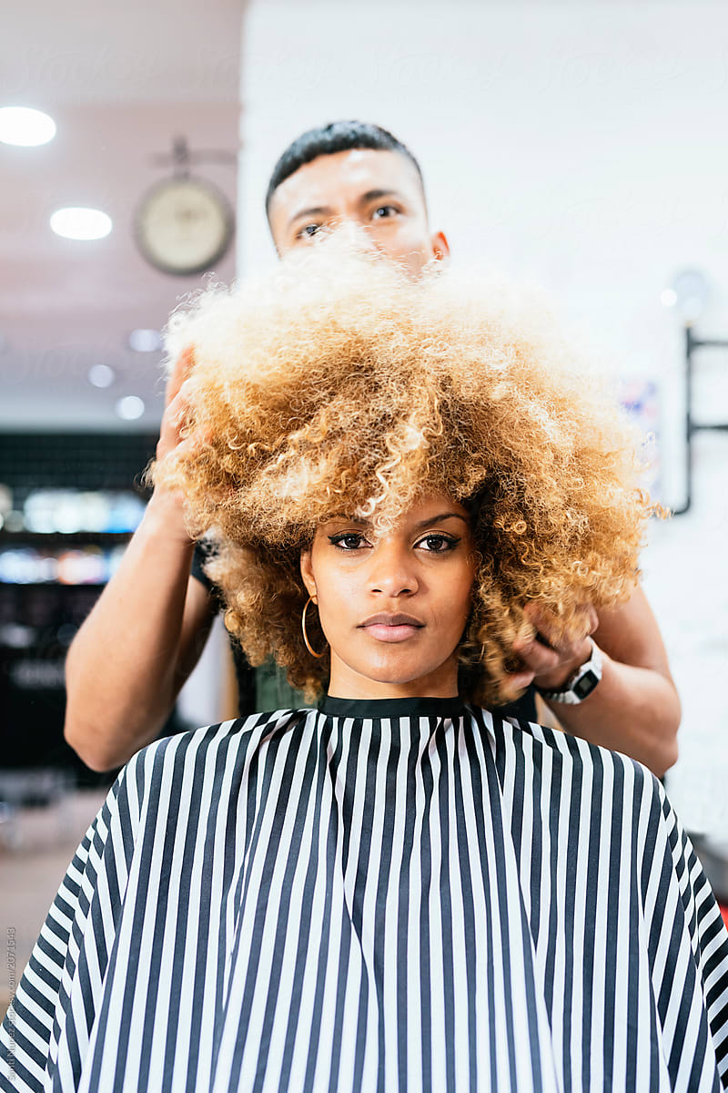 Beautiful afro woman getting haircut by hairdresser in the beauty salon