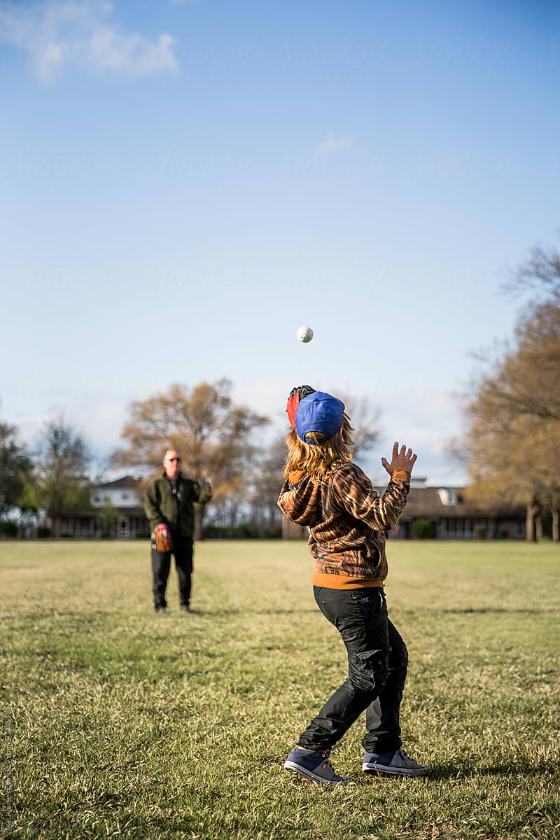 Father and son playing catch in a field in a neighborhood