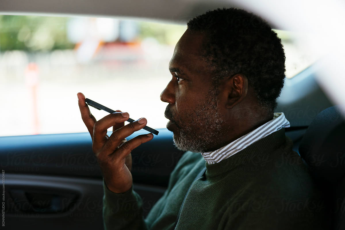 Serious middle age man talking on smartphone in car