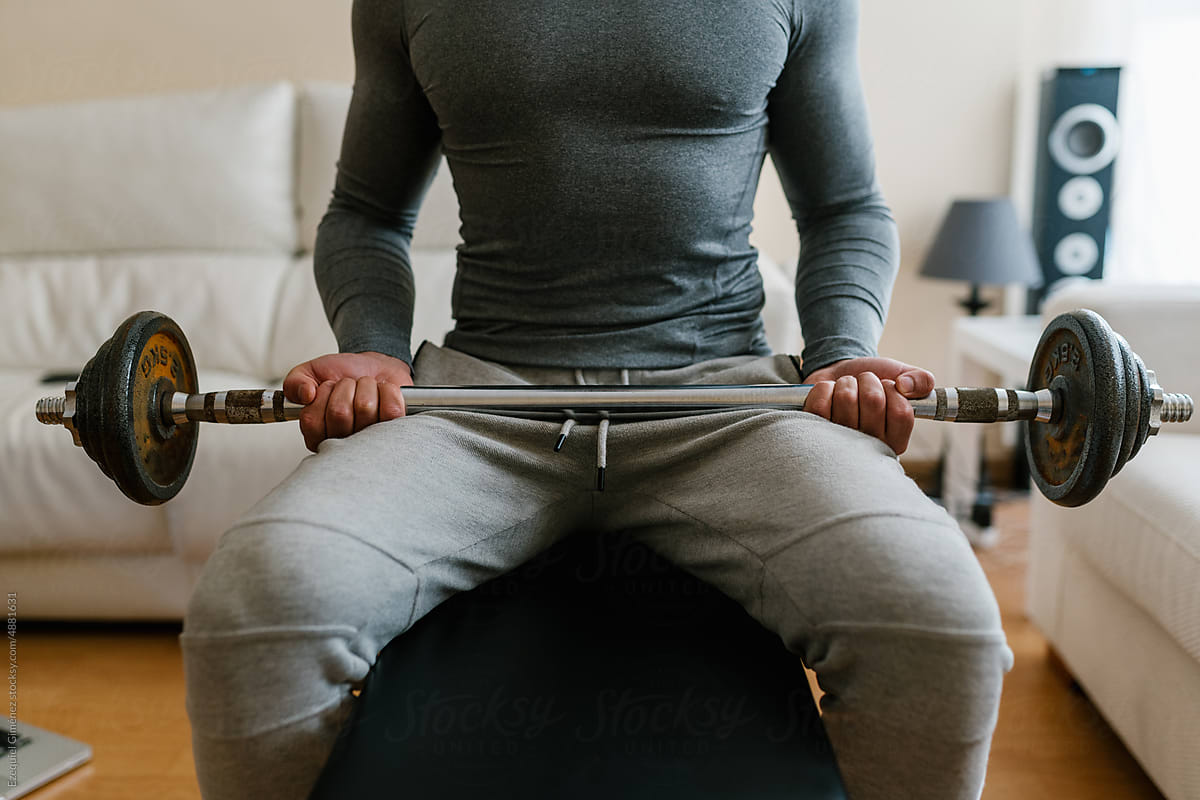 Crop sportsman exercising with barbell at home
