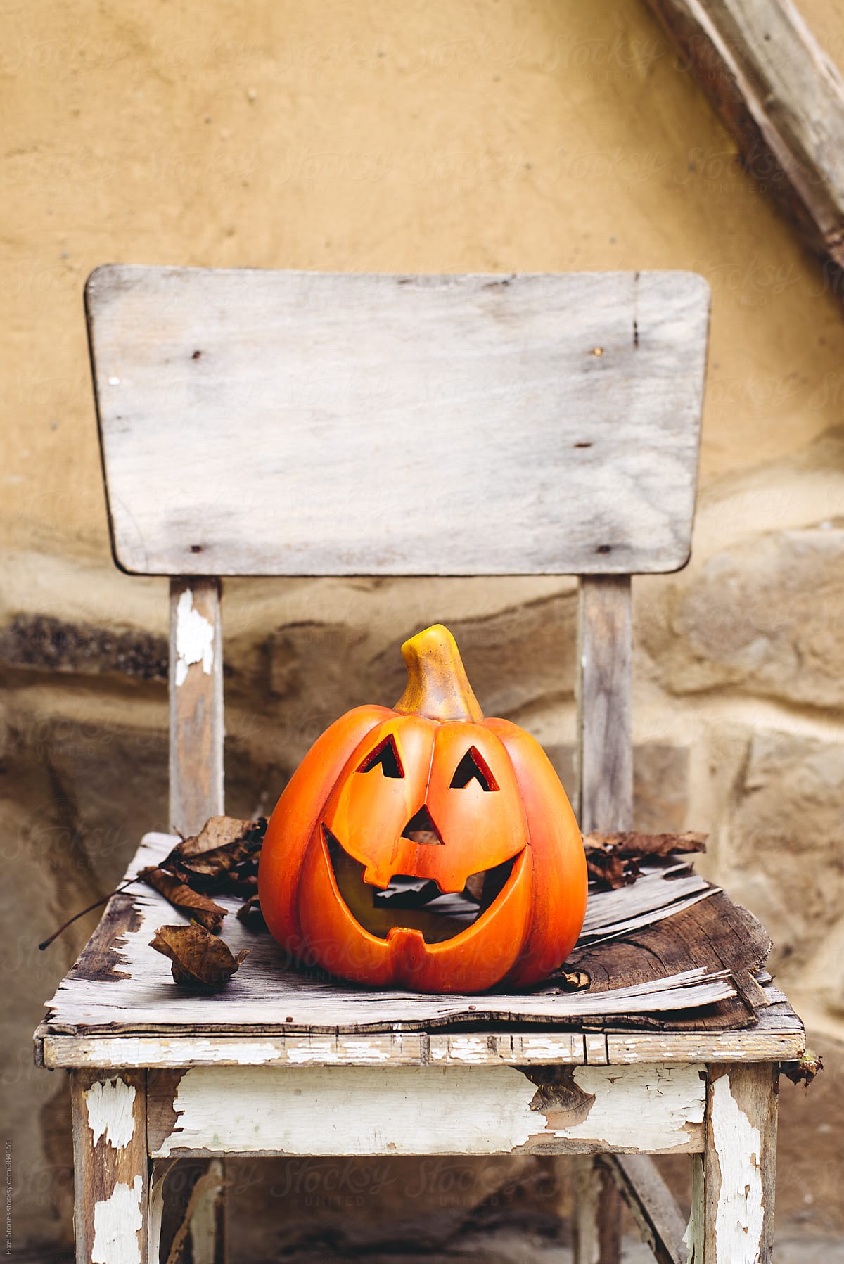 Halloween: ceramic pumpkin on old chair with leaves
