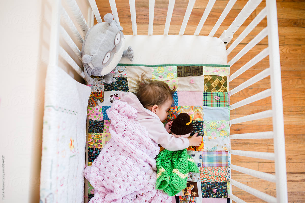 Overhead view of child sleeping in crib