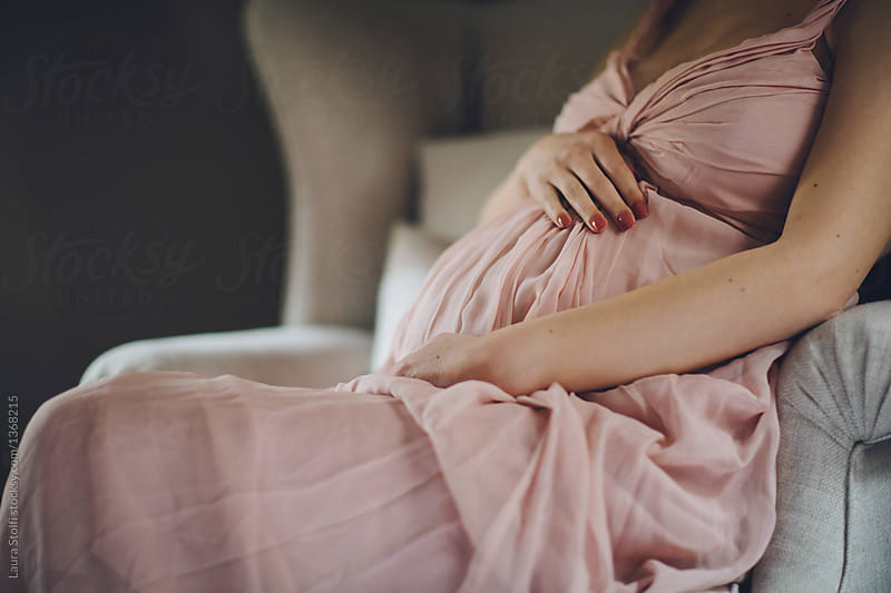 Unknown woman holds her pregnant belly while wearing a