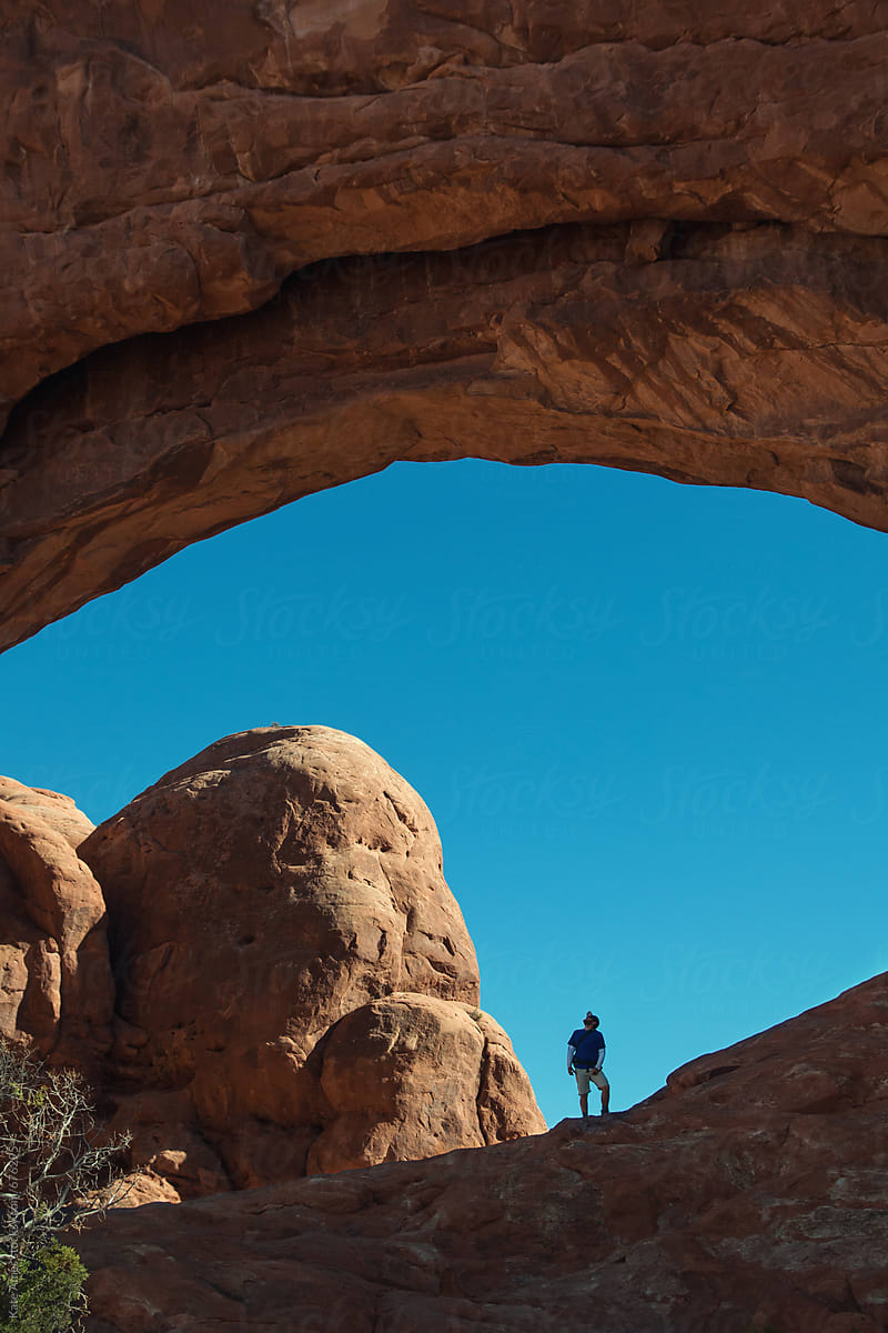 Man standing in opening of arch in Arches National Park, Utah.
