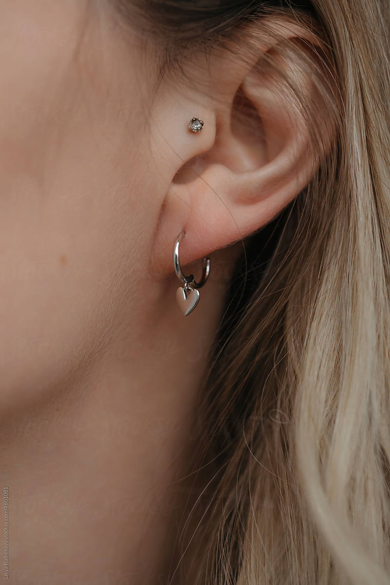 Closeup ear with earrings and piercing - silver jewelry