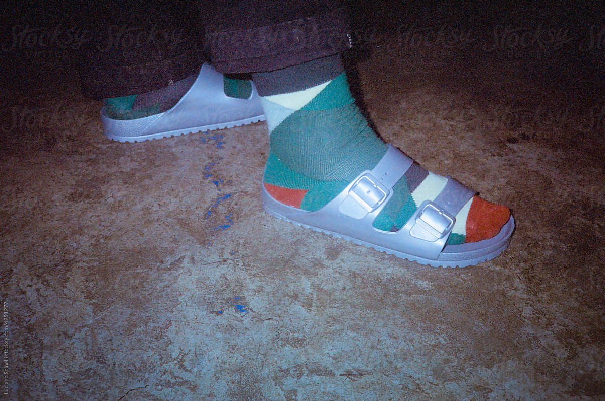 Man wearing grey sandals with colourful socks