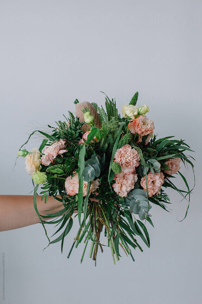 Hand holding bouquet  against white wall