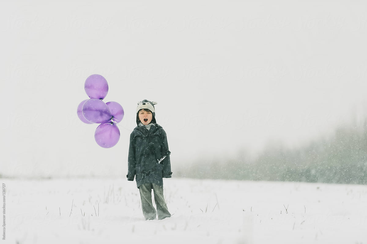 Child in snow with purple balloons