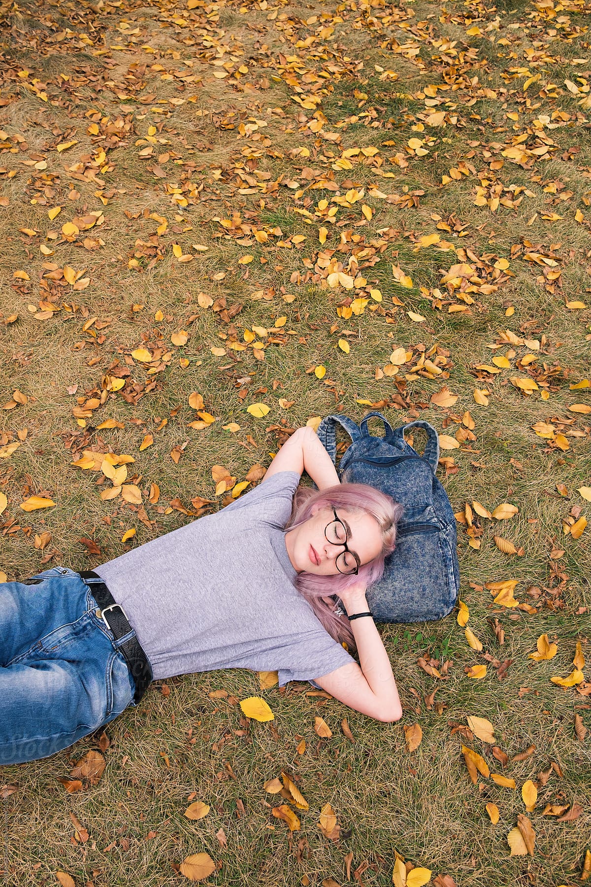 Teen girl having nap in park on rucksack