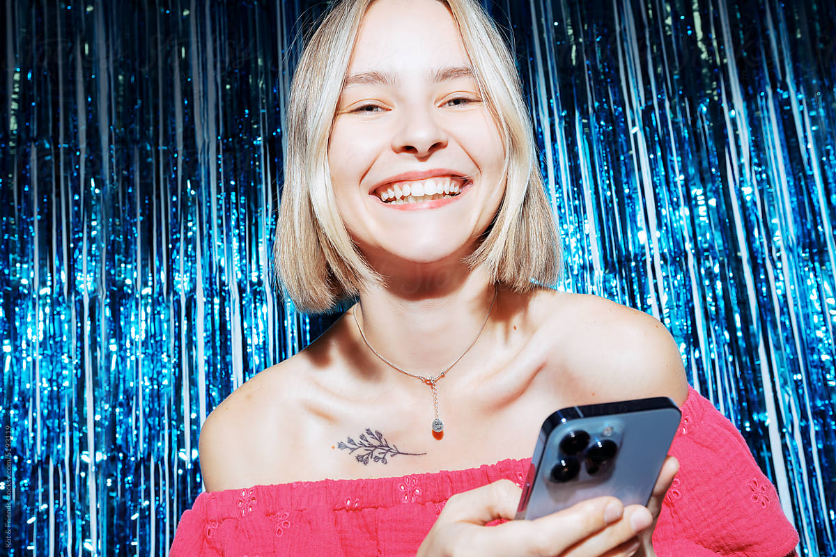 Young Woman With Phone On Blue Tinsel Background