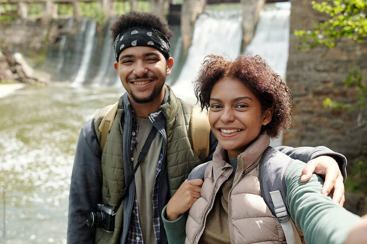 Young Couple On Bank Of River Taking Selfie