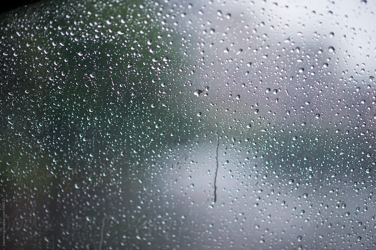 Raindrops beading on glass of car window on wet misty day, view from inside the car
